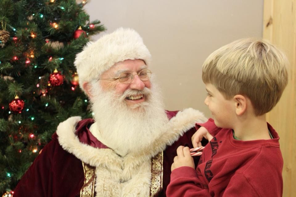 Santa and a small boy smiling at each other 