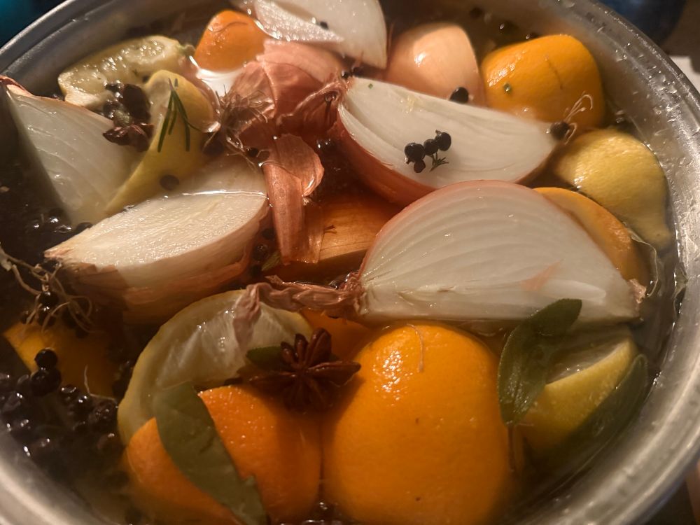 Cider and spices with wedges of lemon, orange and onion 