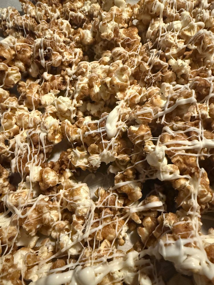 A big tray of cinnamon caramel corn with pecans and white candy coating 