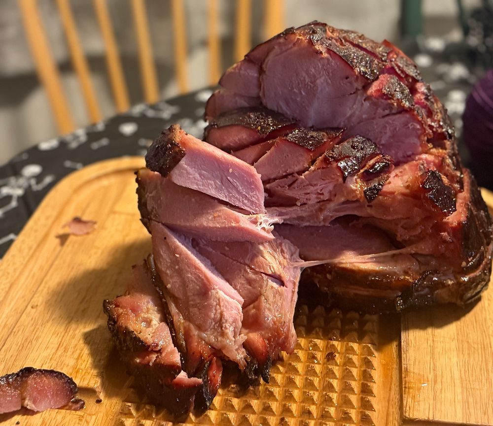 A ham partially carved on a wooden cutting board. 