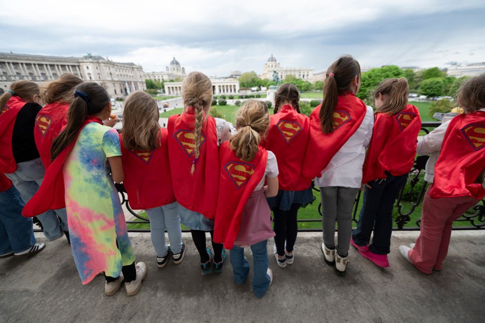 Mädchen mit Supergirl-Capes stehen am Balkon der Präsidentschaftskanzlei
