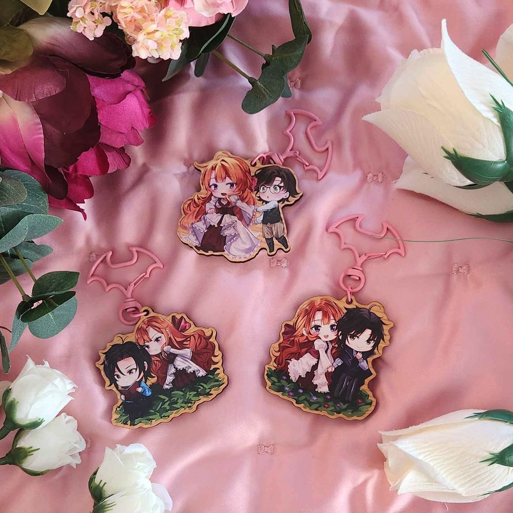 photo of 3 chibi keychains on a pink backdrop surrounded by white and pink flowers
