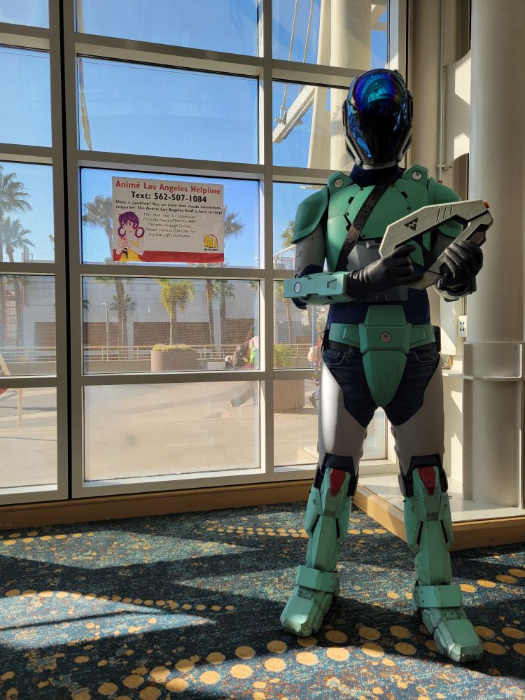 Wide shot of the armor suit, green armor panels and a fabric base, with a mirrored dome visor helmet