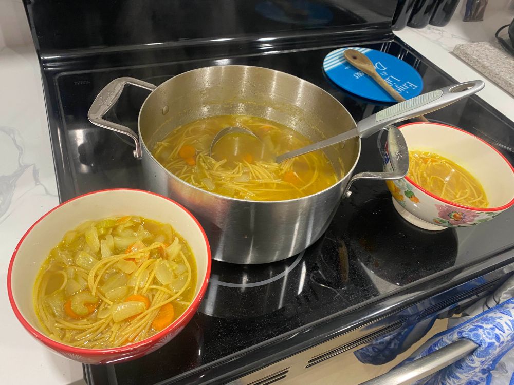 A pot and two bowls of homemade chicken noodle soup that I, the player, made the night of the game. 