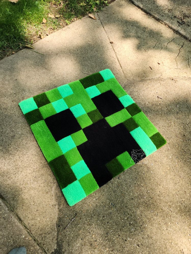 A tufted artwork of the face of minecraft's creeper monster