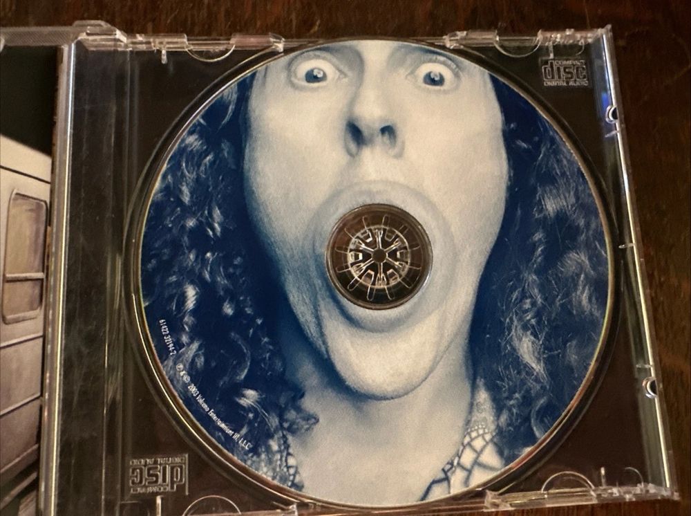 The disc for Weird Al’s “Poodle Hat” album: Weird Al is doing an “o-face” to have the hole of a CD wholly in his mouth.