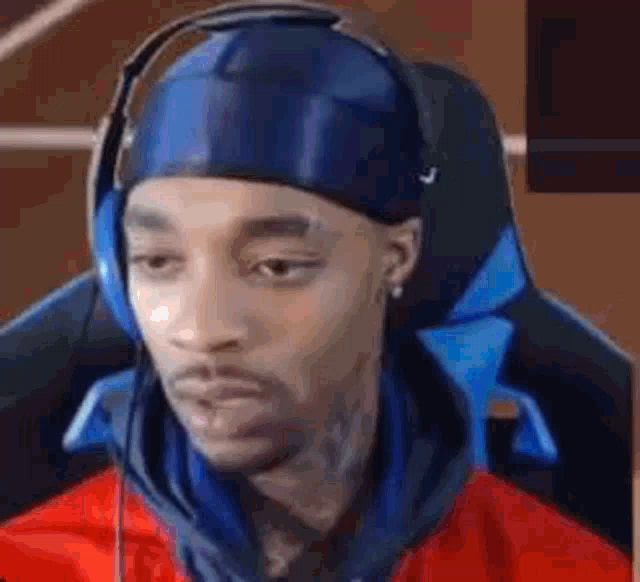 a man wearing headphones and a headband is sitting in a gaming chair .