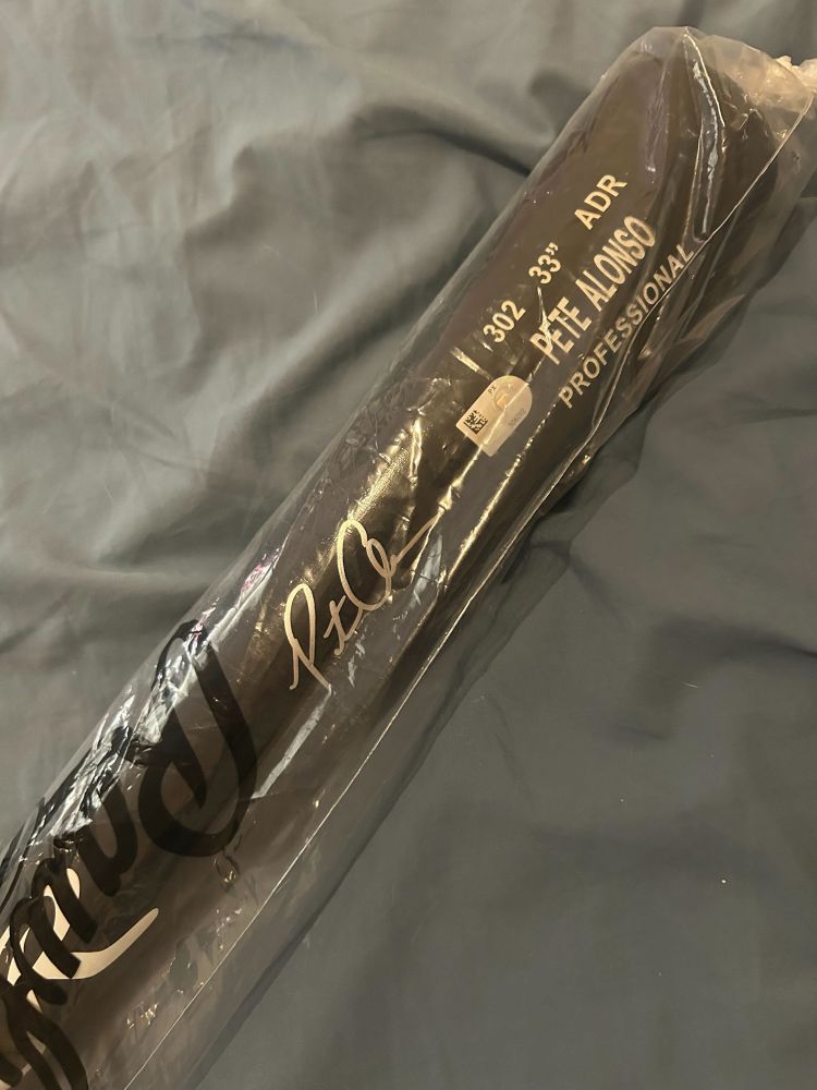 A black baseball bat autographed by Pete Alonso