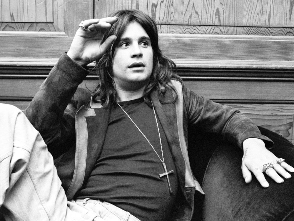 A young Ozzy Osborne sat on a couch