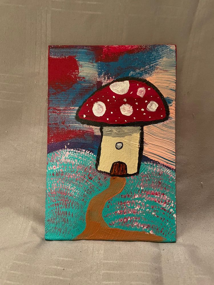 Painting, acrylic on canvas board, of a small mushroom house. The stem is a pale yellow, with a dark brown semi-circular door, and halfway up, a circular porthole style window. The mushroom cap acting as the roof of the house is read with a few large white dots and several small ones. There is a tan/brown path leading to the door, the grass on either side is green with several spots of red and white blades, the sky in the background is highly abstracted with several varied swatches of color including pink, red, blue, and teal.
