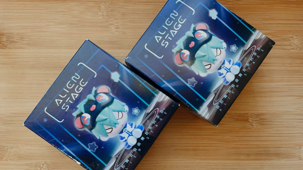 two alien stage figure blind boxes on top of a light brown table