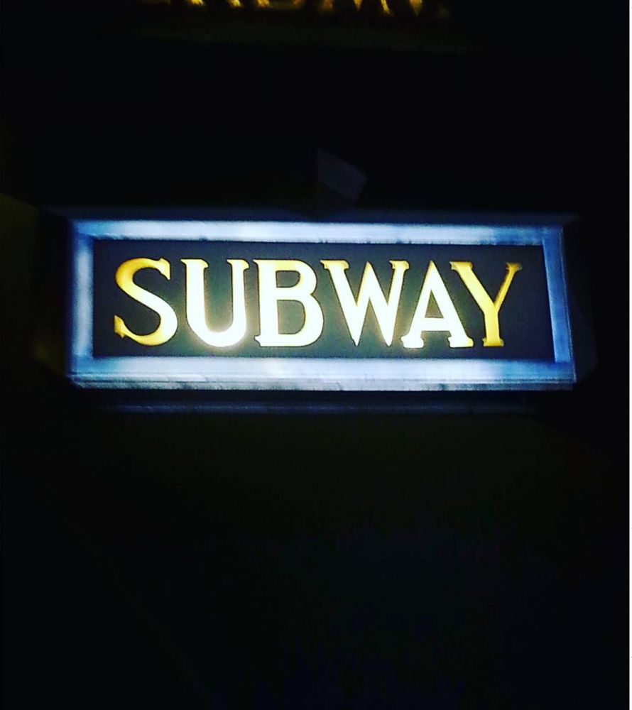 Sign with "Subway" on it. Black background.
