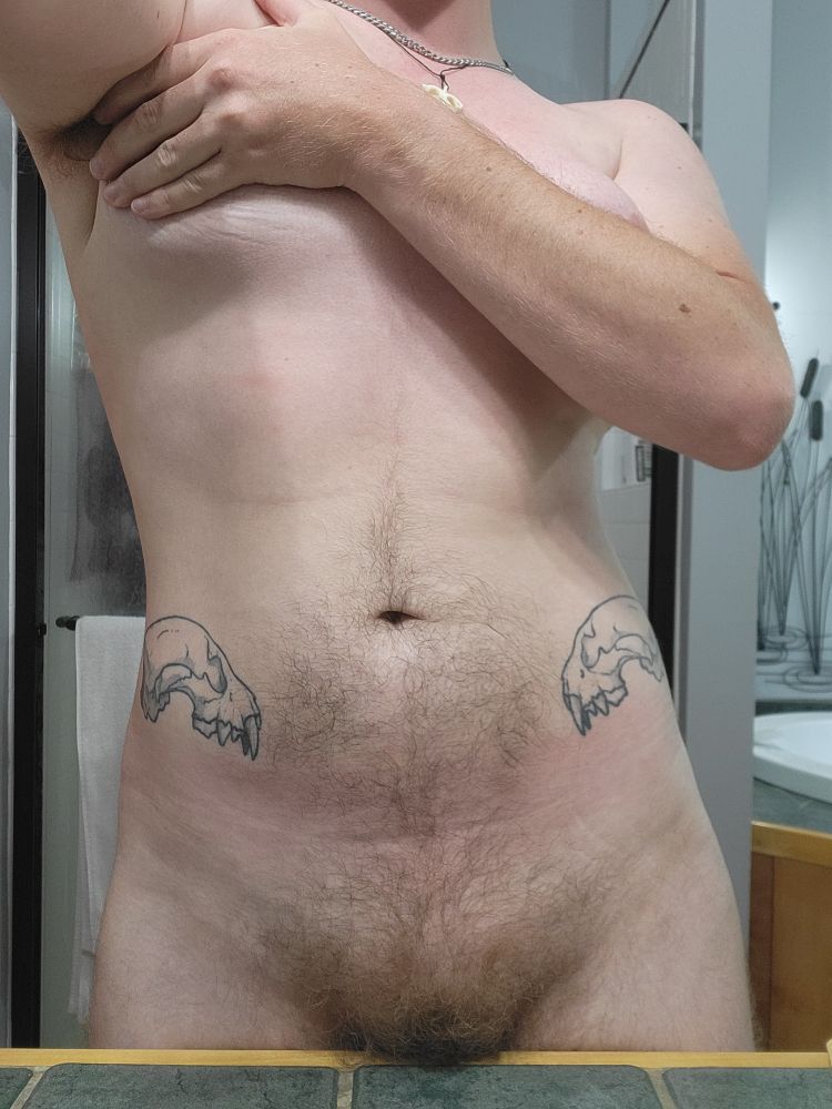 A shot of Blue from his thighs to his shoulders. His pibic mound and bush are just above a tile counter that obscures his legs. He has an arm across his chest.
