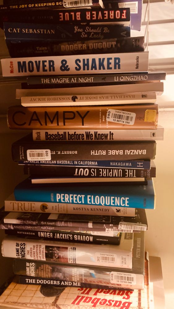 A precarious stack of about fifteen baseball themed books with dramatic side lighting. And one book of Chinese poetry. 