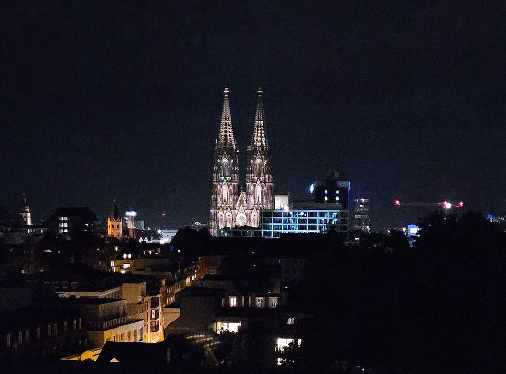 View of the Dom in Köln at night. The two spires of the Dom are lit up with much of the foreground very dark and the sky just a little bit lighter