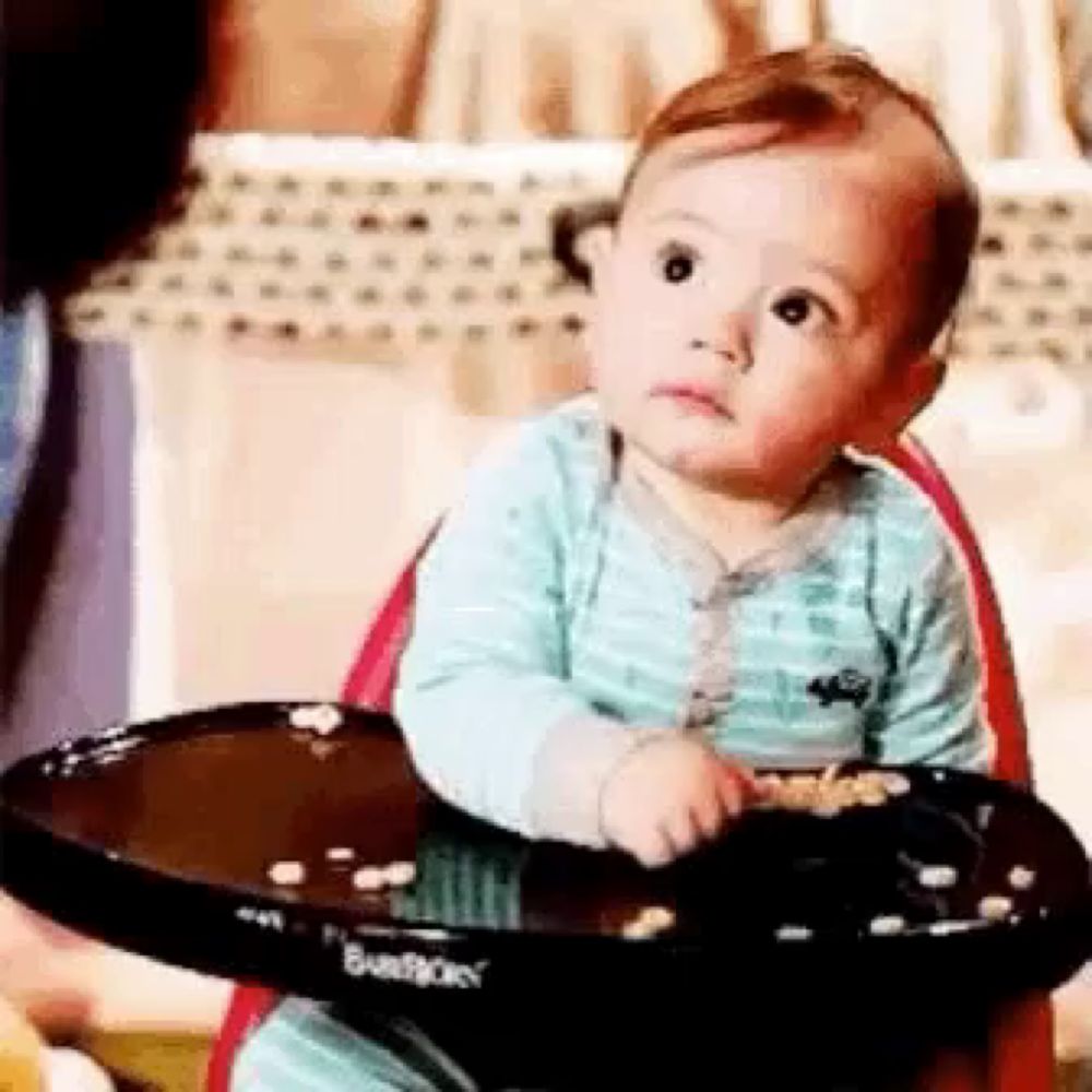 a baby is sitting in a high chair looking at a tray of food .