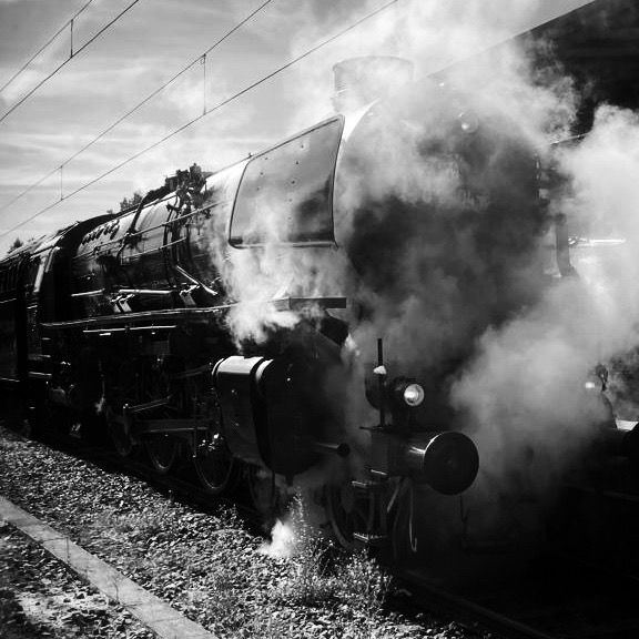 Ein schwarz-weiß Foto einer Dampflok, welche im vorderen Teil im Dunst verloren ist.