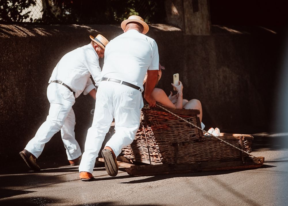 Carreiros pushing a wicker toboggan down a hill
