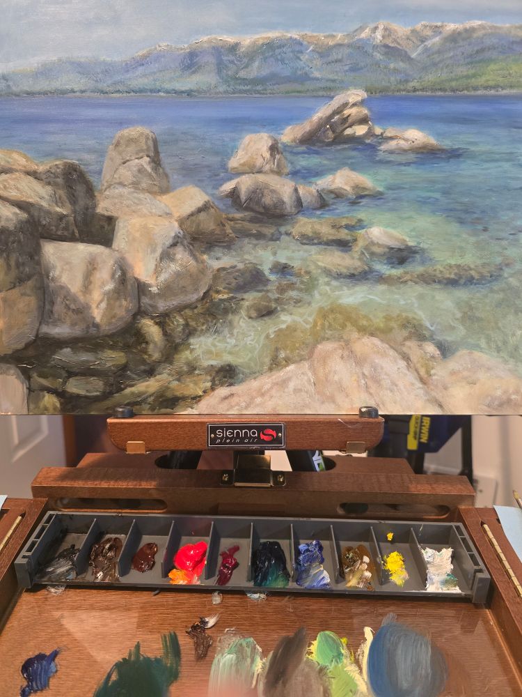 Painting of lake Tahoe en plein air. Rocks and couldn't sitting in turquoise water. 