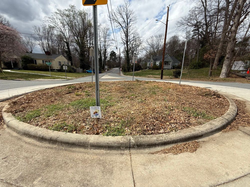 A freshly mowed, mostly dormant garden bed in a traffic circle. 