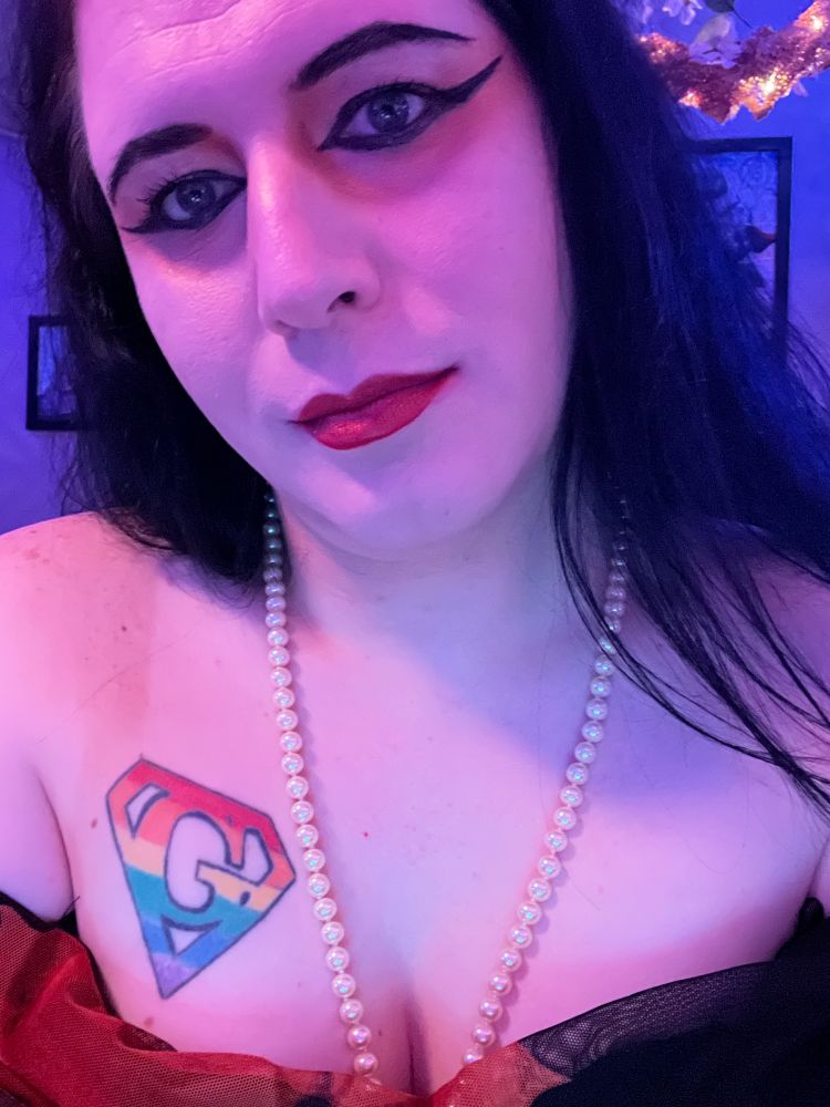 A selfie of OP wearing an orange and black cocktail dress in blue lighting.