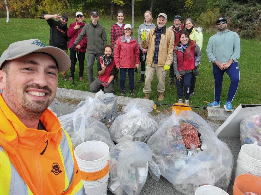 photo of volunteers standing behind large white bags full of trash 