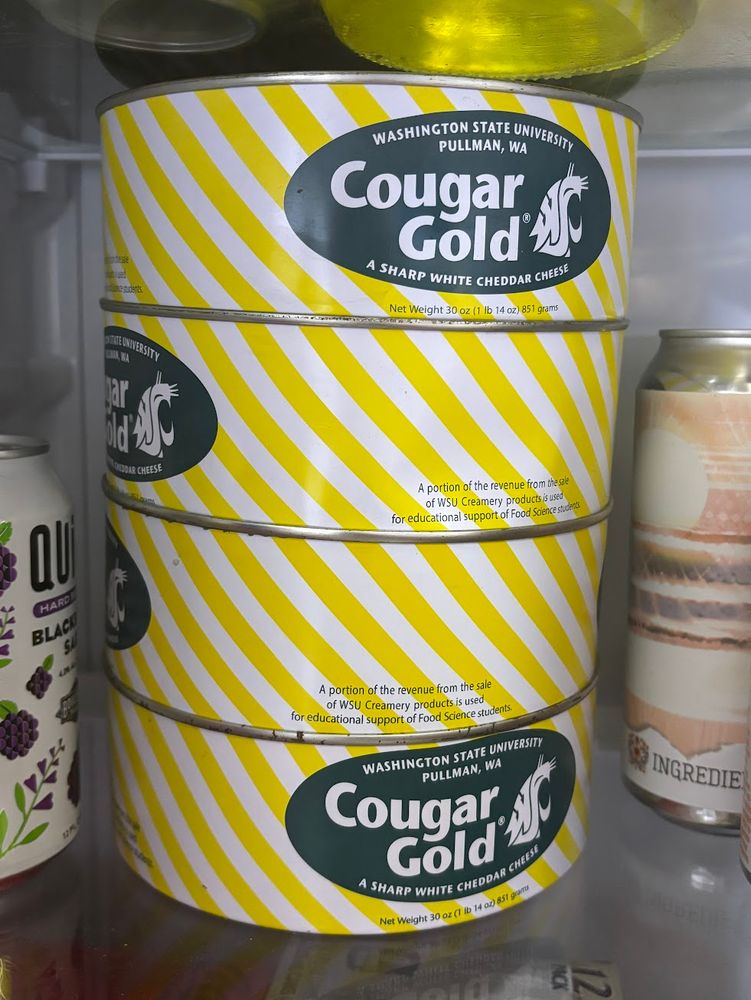 four steel cans of cougar gold cheese in a refrigerator
