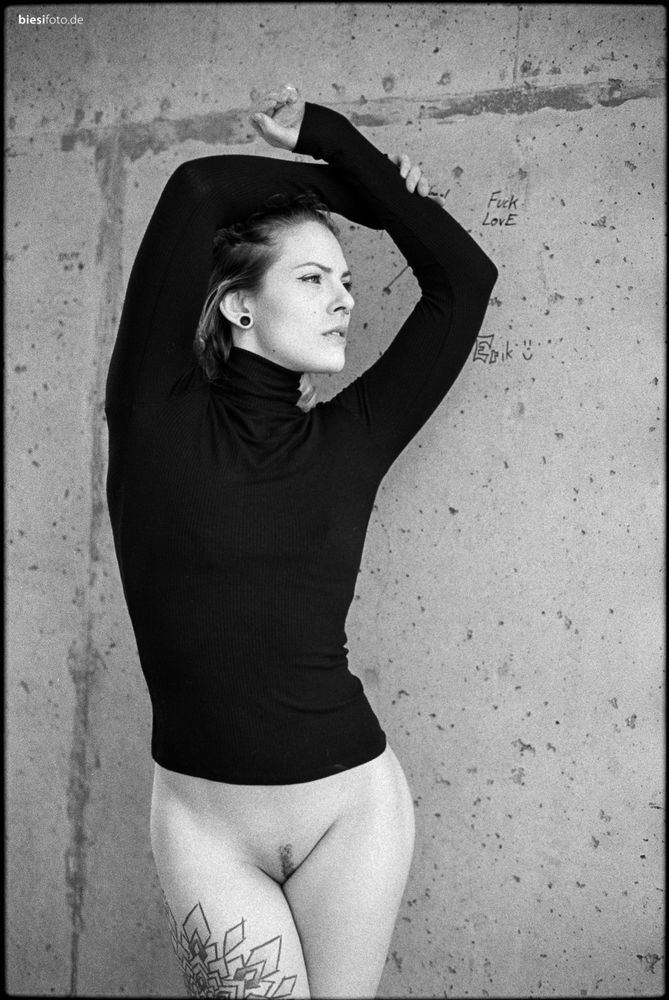 Beautiful young woman posing outdoors bottomless with only a black turtleneck on.