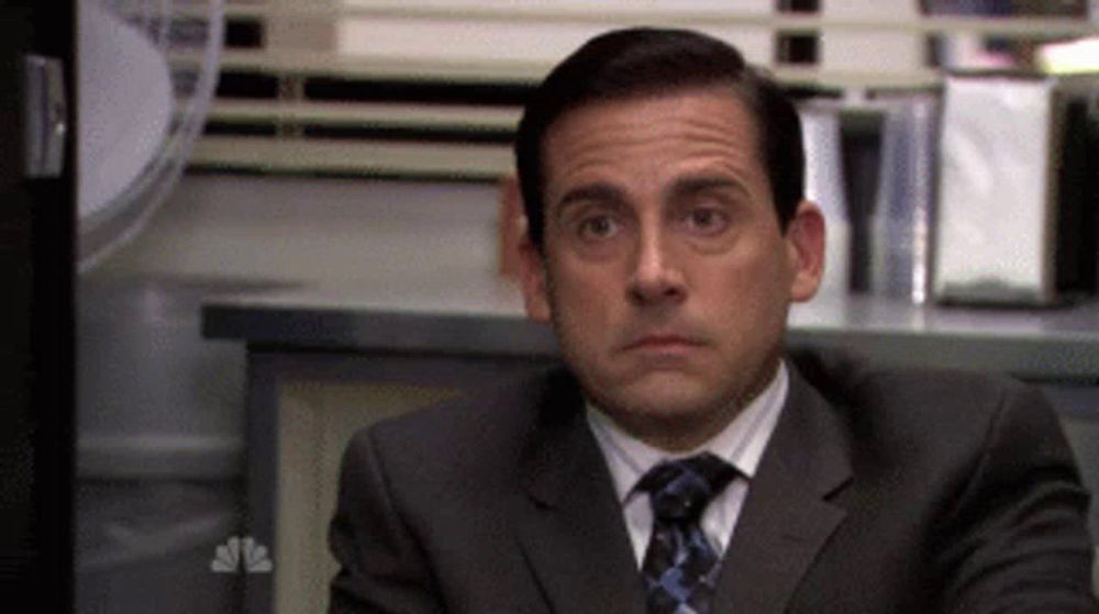 a man in a suit and tie is sitting at a desk in front of a nbc sign