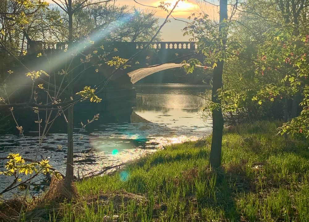 Stone bridge, sun setting behind it and reflecting in the lagoon below.