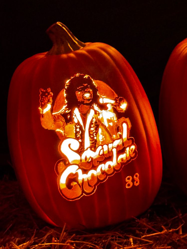 A pumpkin lit up at night. Eddie Murphy’s character Randy Watson is carved into it, with the name of his fictional band Sexual Chocolate and ‘88 - the year Coming to America was released.