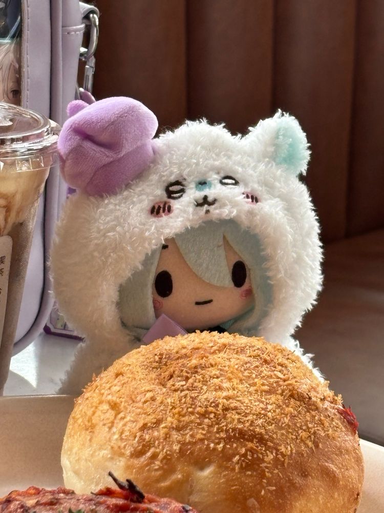 Kanade Yoisaki from Project Sekai as a plushie in a Momonga from Chiikawa costume sitting in front of a curry bread 