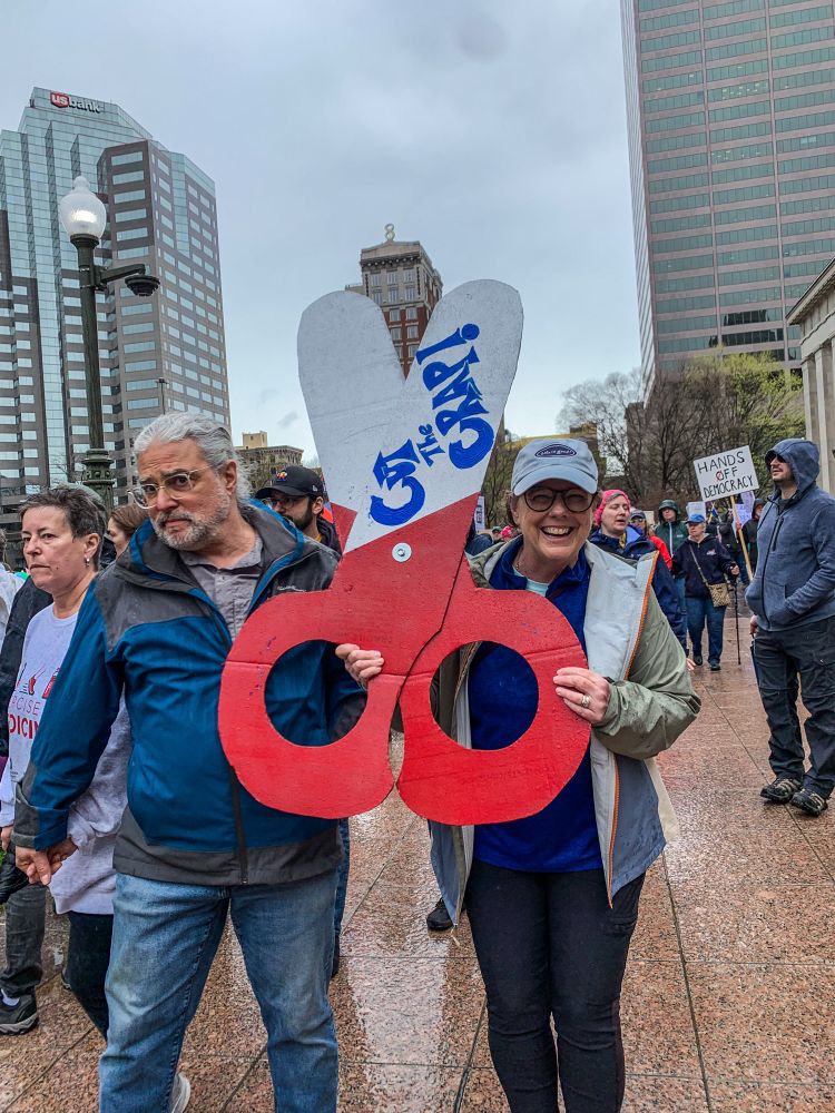 Protestors at the Ohio statehouse for No Kings  with a sign shaped like scissors “cut the crap”