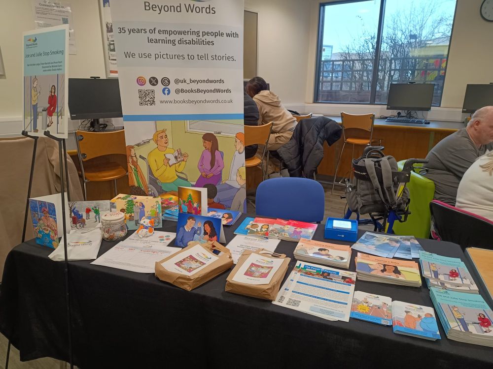 A photograph of a stall at LDCoP24 containing Beyond Words books, leaflets, and Christmas cards.
