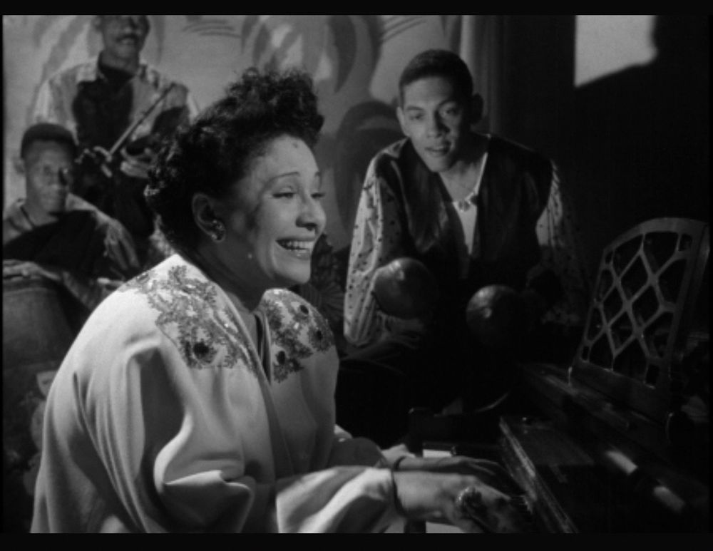 A woman sitting at a piano in a black and white movie