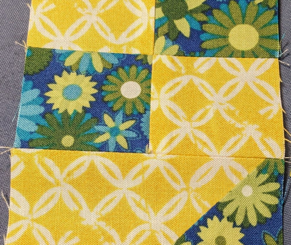 Yellow fabric with a white circular accent pattern matches up along a seam, in a second quilt block.