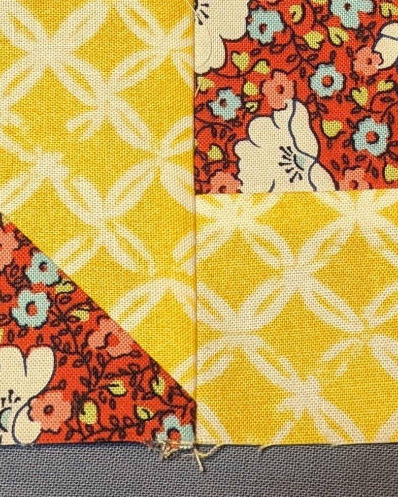Yellow fabric with a white circular accent pattern matches up along a seam in a quilt block.