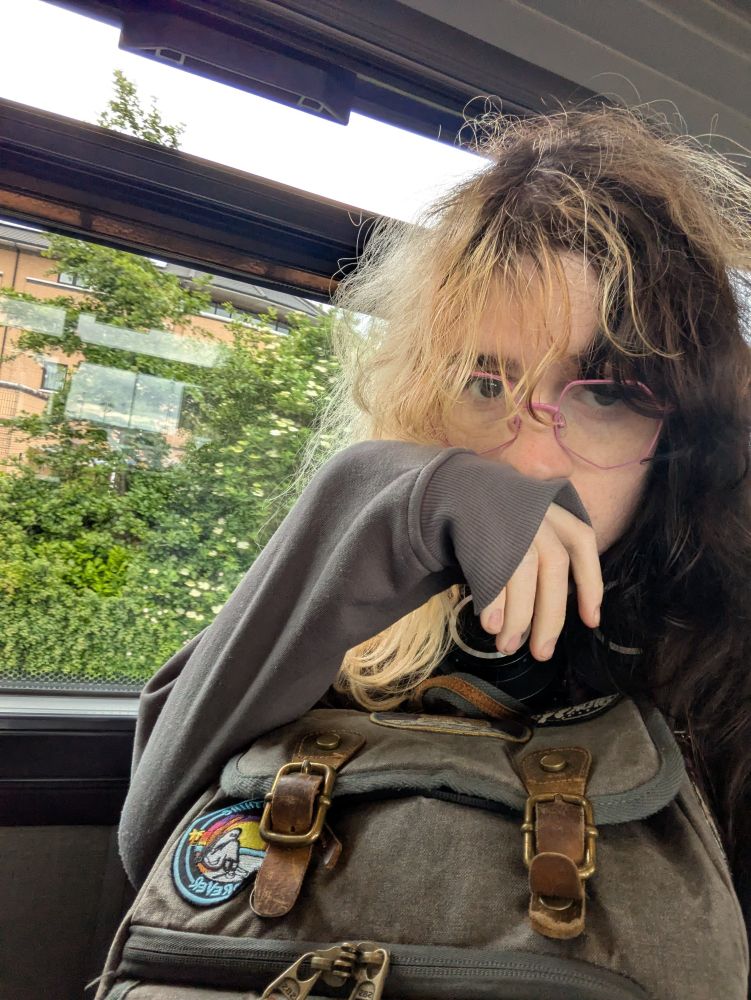 selfie of erín sat by the window of a bus, visibly exhausted (she just spent 6 hours in gatwick airport)