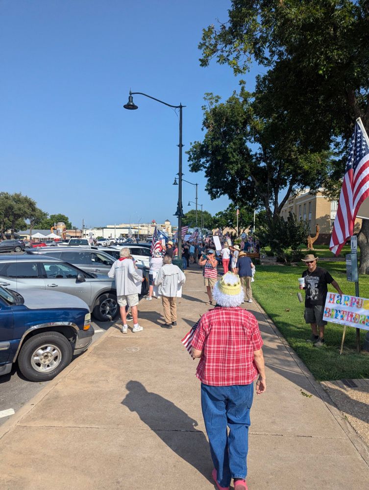 The start of a city block, with a bunch of people with flags and signs