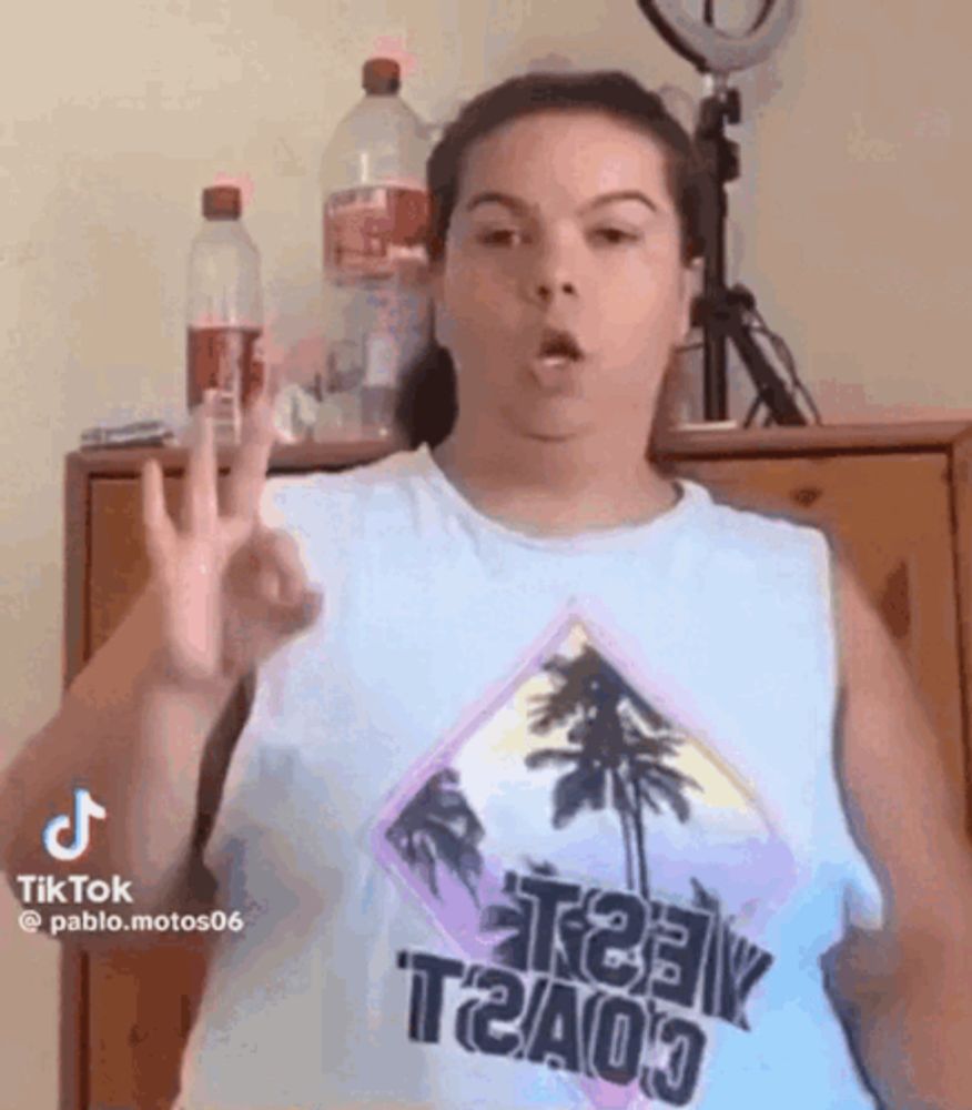 a woman in a tank top is making a peace sign with her hand .