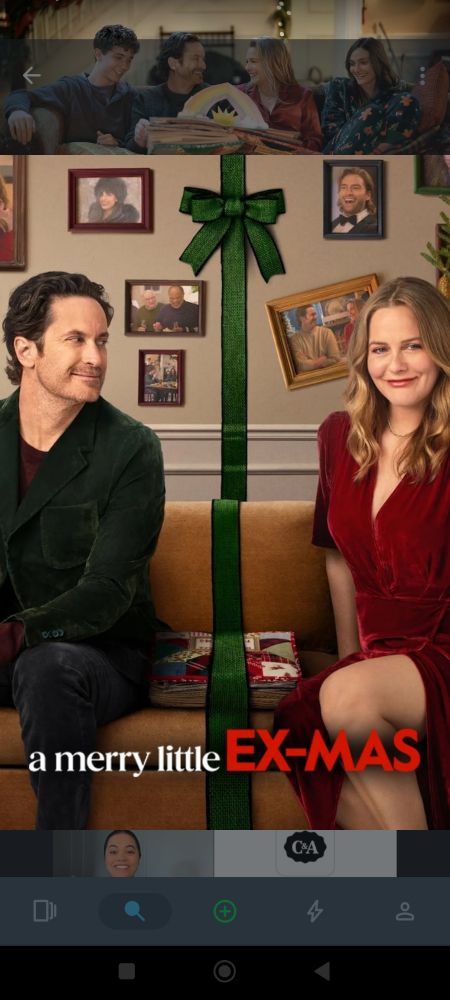 Alicia Silverstone e Oliver Hudson separados por uma fita com laço numa sala de fotos 