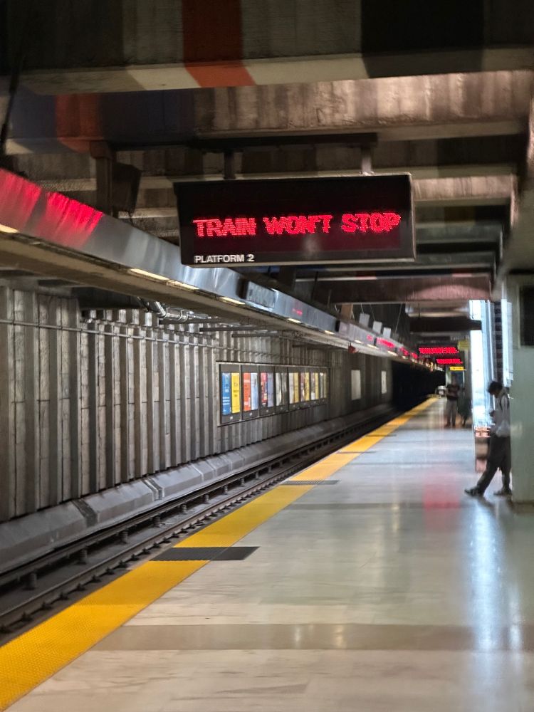 underground subway platform, signs reading "TRAIN WON'T STOP"