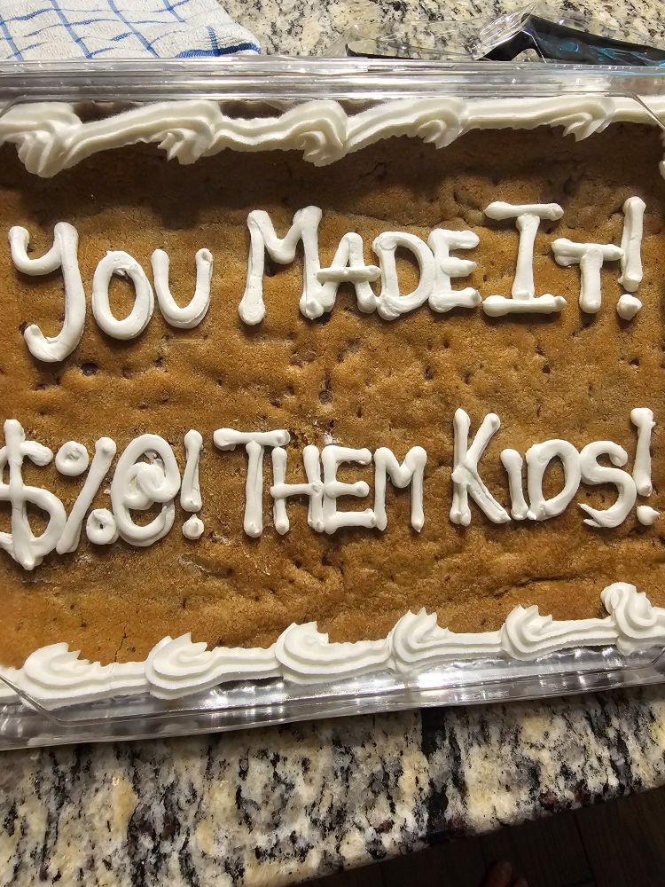 A cookie sheet that spells in icing, "You Made It! $%@! Them Kids."