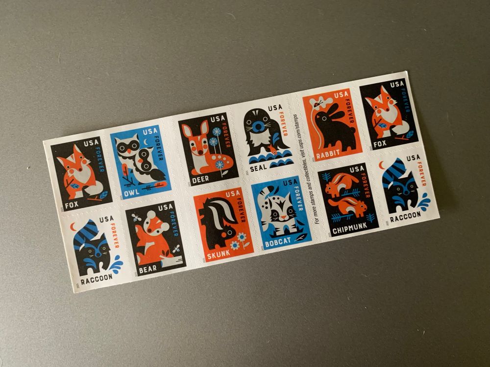 A sheet of US postage stamps featuring a baby fox, baby owls, baby deer, baby seal, baby rabbit, baby raccoon, baby bear, baby skunk, baby bobcat, and baby chipmunks 
