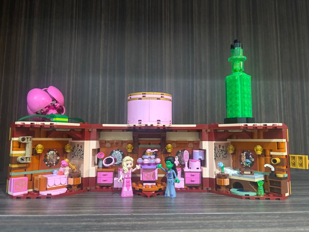 the inside of a lego doll house based on the wicked movie. it looks like a box for sharing jewelry but opens up to reveal a model of the dorm rooms from the film as well as lego “mini doll” figures of the two main characters