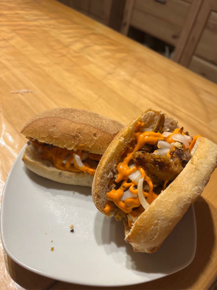 Zwei Weizenbrötchen mit like Döner, Zwiebel und orangener Sauce