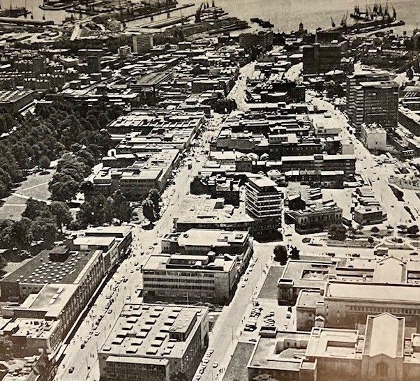 Black and white photograph showing roofs of buildings along Above Bar and the High Street, the Civic Centre in the foreground and ships moored in the docks in the distance
