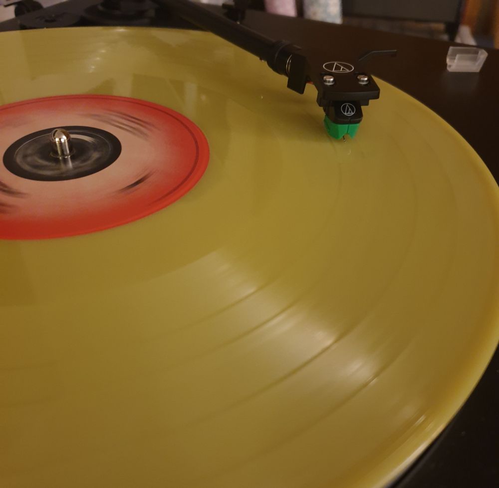 Yellow 180gm vinyl disk with red eye label on turntable 
