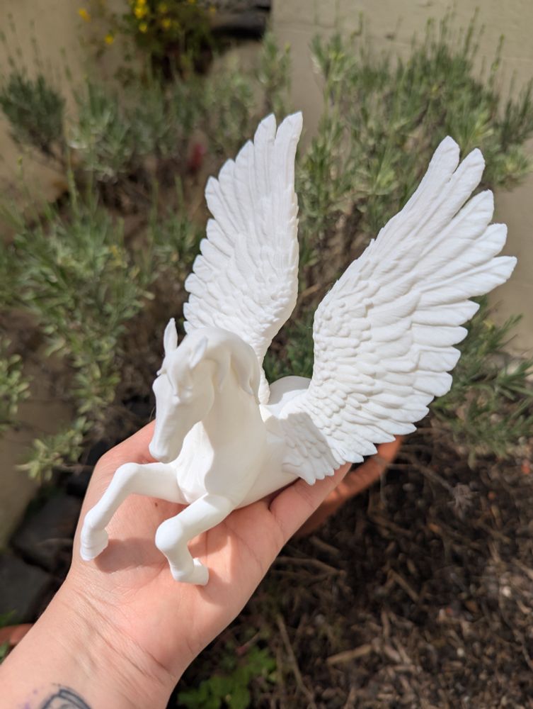 A white pegasus kindle holder on a hand
