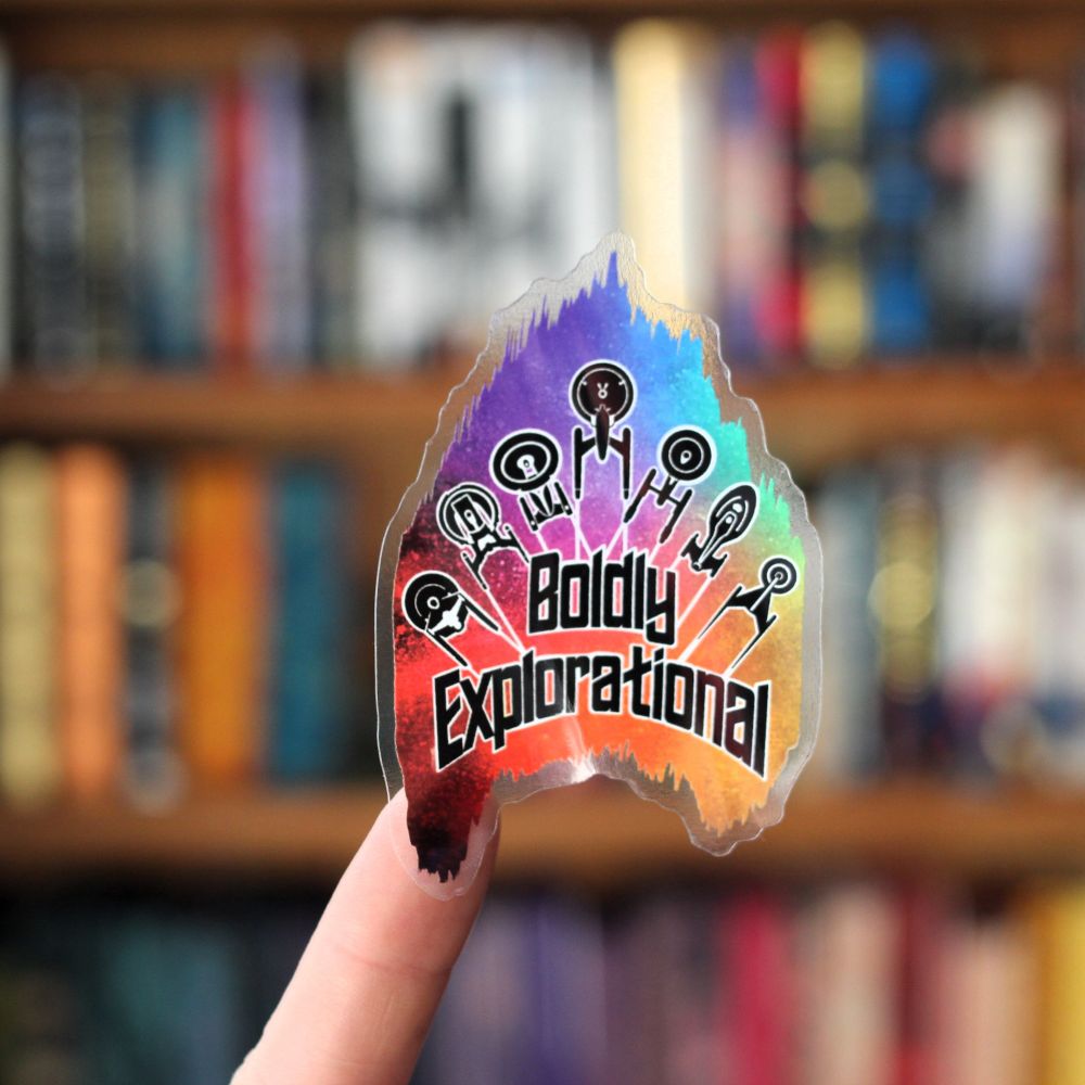 A Star Trek themed sticker, with a rainbow background, featuring 7 ships and the phrase "boldly explorational"